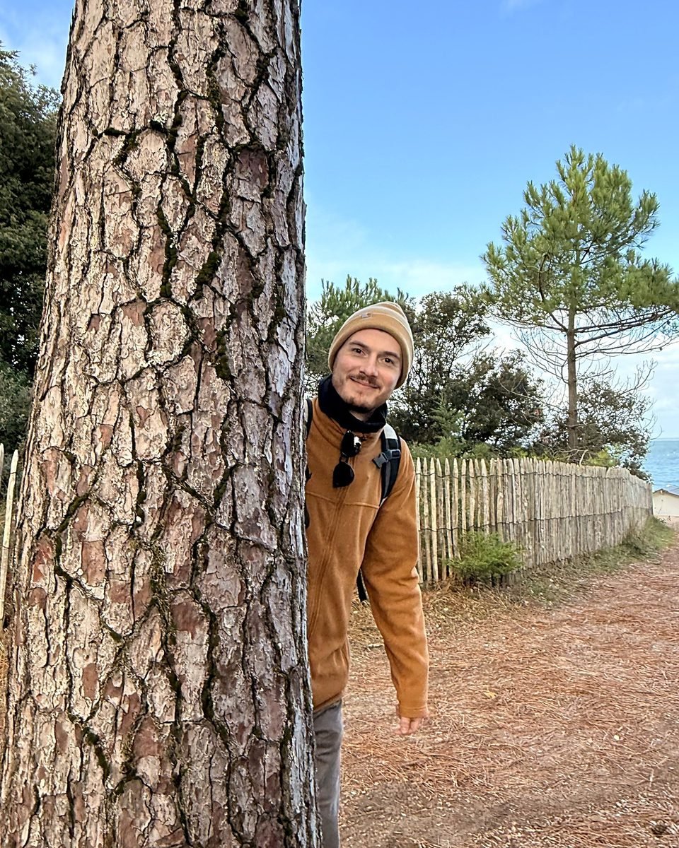 Alexander laughing behind a tree